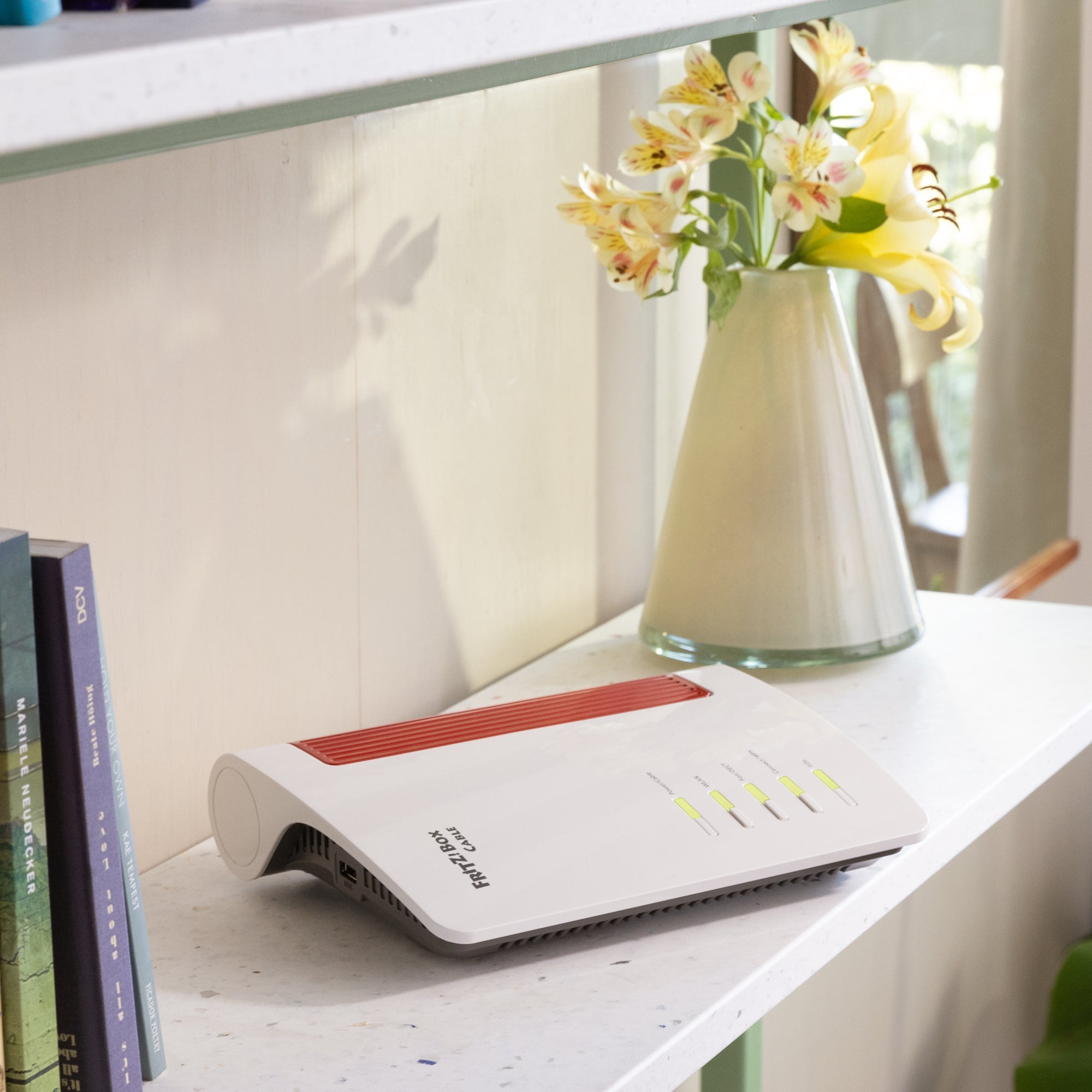 FRITZ!Box 6670 Cable router on a shelf with books, offering Wi-Fi 7 for enhanced streaming and gaming.