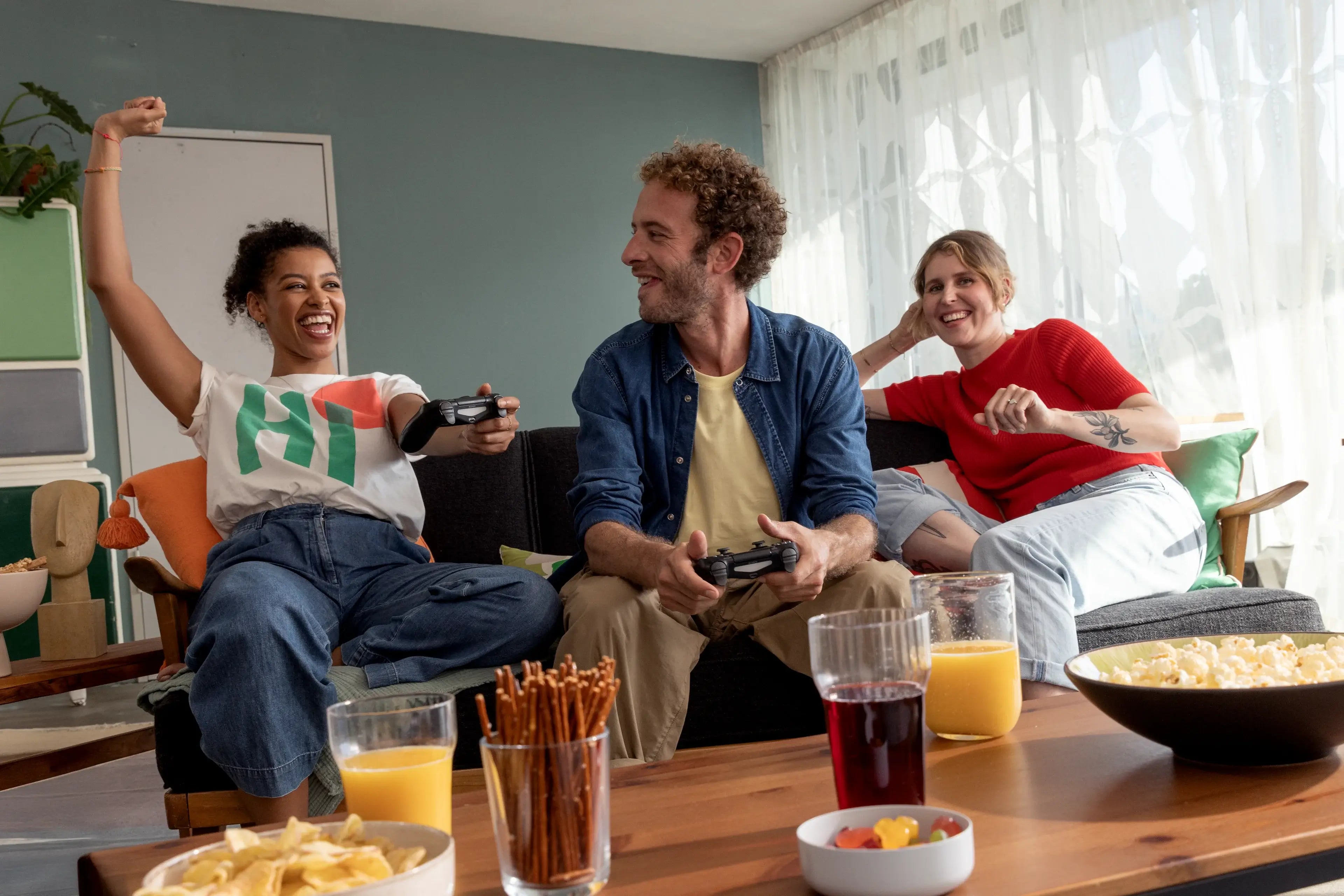 Junge Leute spielen Videospiele, haben Spaß und genießen Snacks bei einem Treffen.